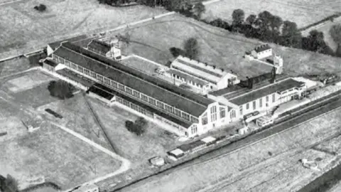 Banbury Historical Society The real factory is seen in a black and white image. Low Art Deco style buildings surrounded by fields.