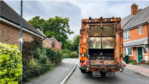 Getty Images The back of an orange bin lorry in a street.
