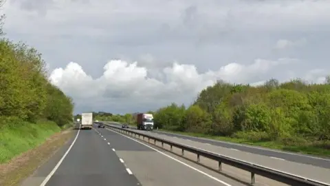 Google A14 road in daylight with two trucks in the distance