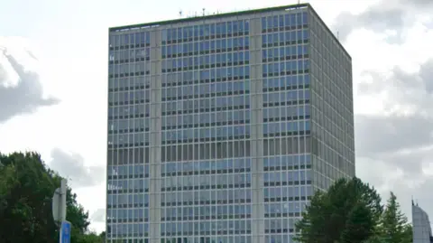 Google Image shows the headquarters of the Driver and Vehicle Licensing Agency (DLVA) in Swansea. It is a modernist-style glass and concrete building of about eight or nine storeys. 