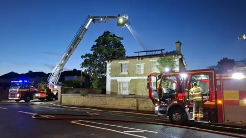 HIWFRS Fire engines alongside a derelict building where a fire has destroyed its roof.