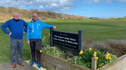 Ian Simpson and John Graham standing in front of a golf course