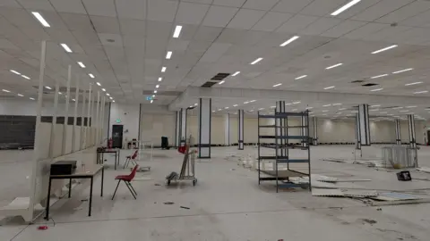 The Market Gallery The inside of the former Wilko store. Wall partitions have been knocked over and torn apart. Broken walls and trolleys litter the large white room.