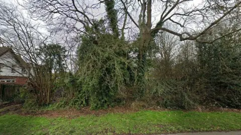 A fence with lots of trees next to a house