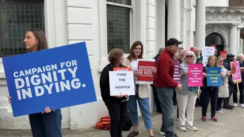 BBC Campaigners with placards for and against the Assisted Dying Bill gather outside the Isle of Man's white parliament building.