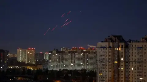 Reuters Tracers are seen in the night sky as Ukrainian servicemen fire at a drone over Kyiv, Ukraine, October 21, 2024. 