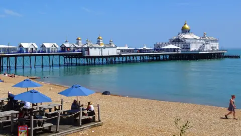 BBC Weather Watchers/ Peter and Leah A man walking across golden sands bordering bright blue seas in Eastbourne