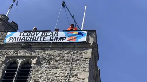 Holy Trinity Church Rayleigh A sign that reads "teddy bear parachute jump" on the top of the church tower