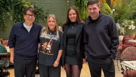Emily's Steven Gerrard and Michael McIntyre are posing for a picture with two staff members at Emily's. They are all smiling at the camera. 