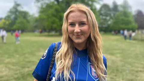 Alice Cunningham/BBC Woman with long blonde hair in a blue Ipswich Town shirt.
