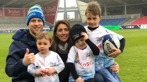 Robinson family A family wearing rugby shirts smiling. Three children and two adults.