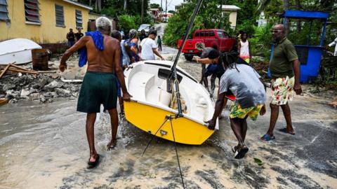 Residents clear a boat from the street as it gets flooded after the passage of Hurricane Beryl in the parish of Saint James, Barbados, near Bridgetown on July 1, 2024.