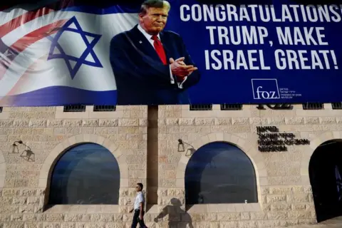 EPA A man walks past a large billboard congratulating US President-elect Donald Trump, on the facade of Friends of Zion Museum in Jerusalem, 07 November 2024.