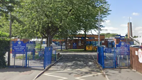 Google Maps The front gates of Bilston primary school. There is a large tree on the left, and the school is in the background. To the right, inside the gates, is a car park