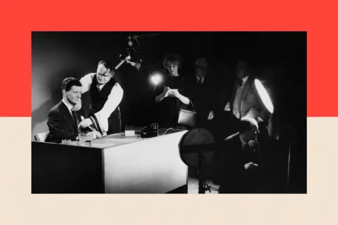 Getty Images BBC newsreader Richard Baker tries on different ties at the news studio 