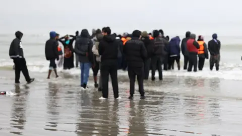 A group of people standing on a beach. 