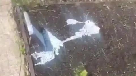 A small gravestone with paint splashed over it 