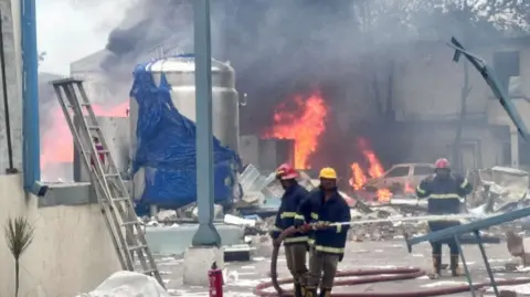 Fire and rescue officials seen working to douse the flames at the blast site