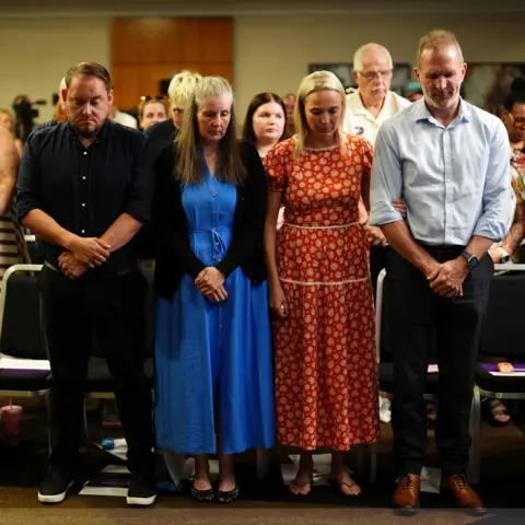 Jacob King/PA Wire Four people - Gary Andrews, Sarah Andrews, Sarah Hawkins and Jack Hawkins - stand side by side. Gary is dressed in a black shirt and black trousers, Sarah wears a long blue dress with a dark cardigan, Sarah wears a long red dress with white detail and Jack wears a light blue shirt with dark trousers.