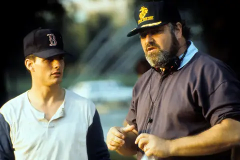 Getty Images Tom Cruise in a baseball shirt and cap looking at Rob Reiner, speaking on the set of A Few Good Men with heaphones and cap