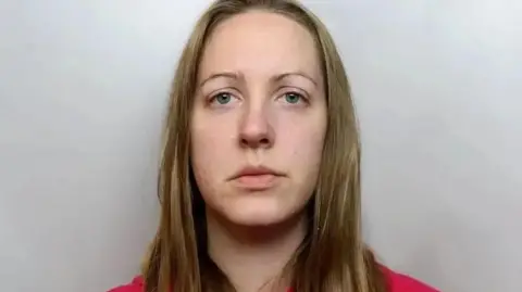 Police custody image of Lucy Letby with long blond hair and red top.
