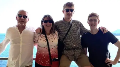 Paul, Jacqui and their two sons stood with the ocean in the background