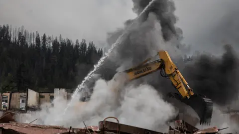 Reuters Fire crews work to cool down hotspots at Maligne Lodge, Jasper