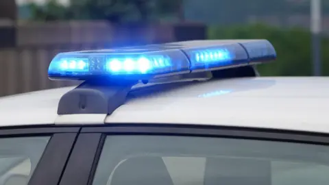 Blue lights flashing on top of a white police car