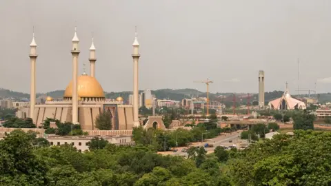 Getty Images Abuja's main mosque and cathedral seen amidst a canopy of trees and cranes.