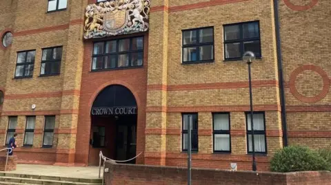 Brian Farmer/BBC St Albans Crown Court: A building made of brown and red bricks. The words "Crown Court" are written over the entrance, beneath a crest.
