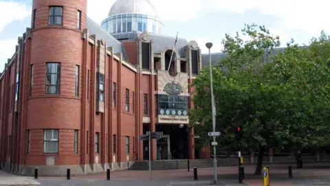 Exterior of Hull Crown Court a three-storey red brick build with a glass dome on the roof and a large central doorway with a paved forecourt.