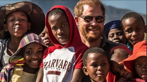 Getty Images Prince Harry pictured with a group of children during a visit to Matlameng – Ha Mahlehle in the Leribe region with Sentebale in 2024