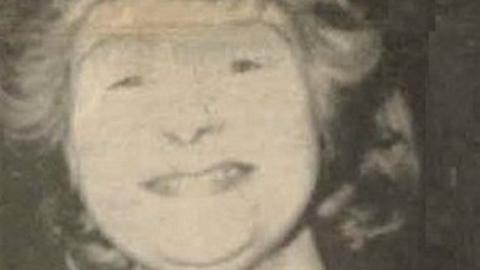 A grainy, black and white close-up image of Carol Morgan smiling towards the camera