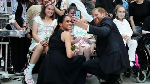 Getty Images Meghan, Duchess of Sussex and Prince Harry, Duke of Sussex pose for a selfie with children and their families during a visit to the Royal Children’s Hospital on April 14, 2026 in Melbourne, Australia.