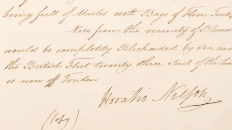 A close-up image shows the lower section of a handwritten historical letter in brown ink on aged paper, with neat cursive lines of text and the clear signature “Horatio Nelson” at the bottom right alongside a small handwritten note reading “copy.”