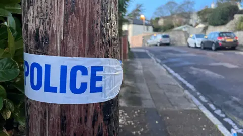 Police tape on a post in Shirburn Road, Torquay