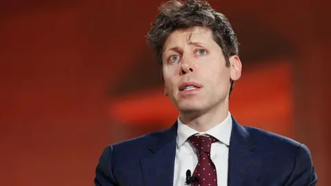 Sam Altman against red background, wearing blue suit and red tie with white dots, looks up and to the side