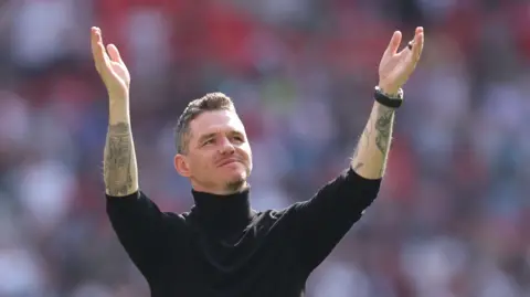 Manchester United manager Marc Skinner holds his hands in the air