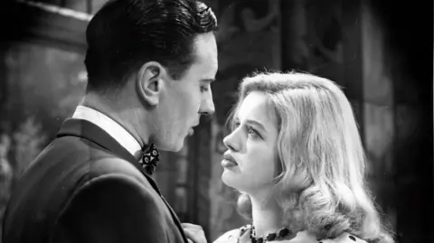 Diana Dors as a young woman looking at actor Robert Ayres in their roles in Face to Face.