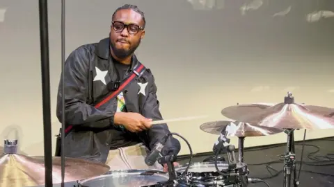 Matty Brown sits at a drum kit