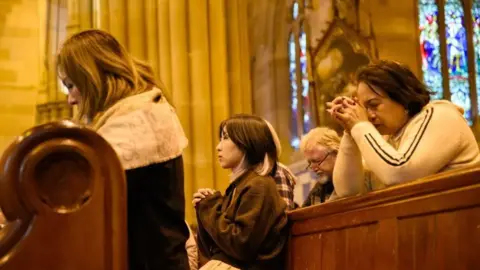 People pray during a Mass at The Cathedral of St Stephen in Brisbane, Australia