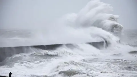 Waves crash over a pier during a previous storm in Newhaven, England