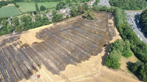 Nottinghamshire Police Aerial image of a wheat field between a busy road and a line of housing which has been blacked by fire