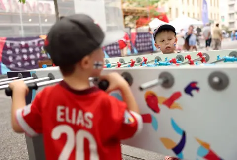 Getty Images Two small children play table football in a fan zone