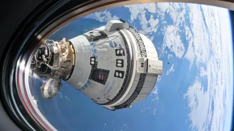 A cápsula Starliner da NASA Boeing, como vista pela janela da estação espacial internacional. A nave é em forma de funil, principalmente branca, mas com o que parecem ladrilhos pretos - o logotipo azul e vermelho da NASA é visível e também o logotipo Starliner em Blue. Você pode ver parte da estrutura da janela através da qual o tiro foi levado e, ao fundo, a água azul e a nuvem branca da terra, com um horizonte curvo visível.