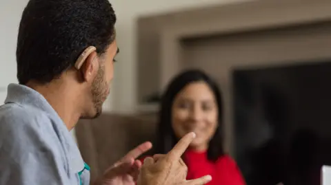 Deaf young people talking in sign language in the living room