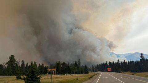 Smoke rising over a highway and trees in Jasper on Wednesday night 
