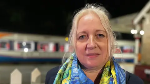BBC Middle-aged woman with blonde hair and a bright scarf