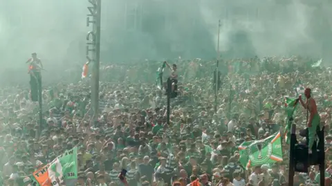 Thousands of fans gathering in the Trongate area of Glasgow with some visible standing aloft traffic lights