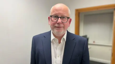 Steve Yemm wearing a dark blue jacket and a white shirt.